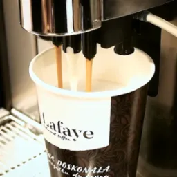 Automatyczny ekspres nalewa kawę do papierowego kubka z logo Lafaye.