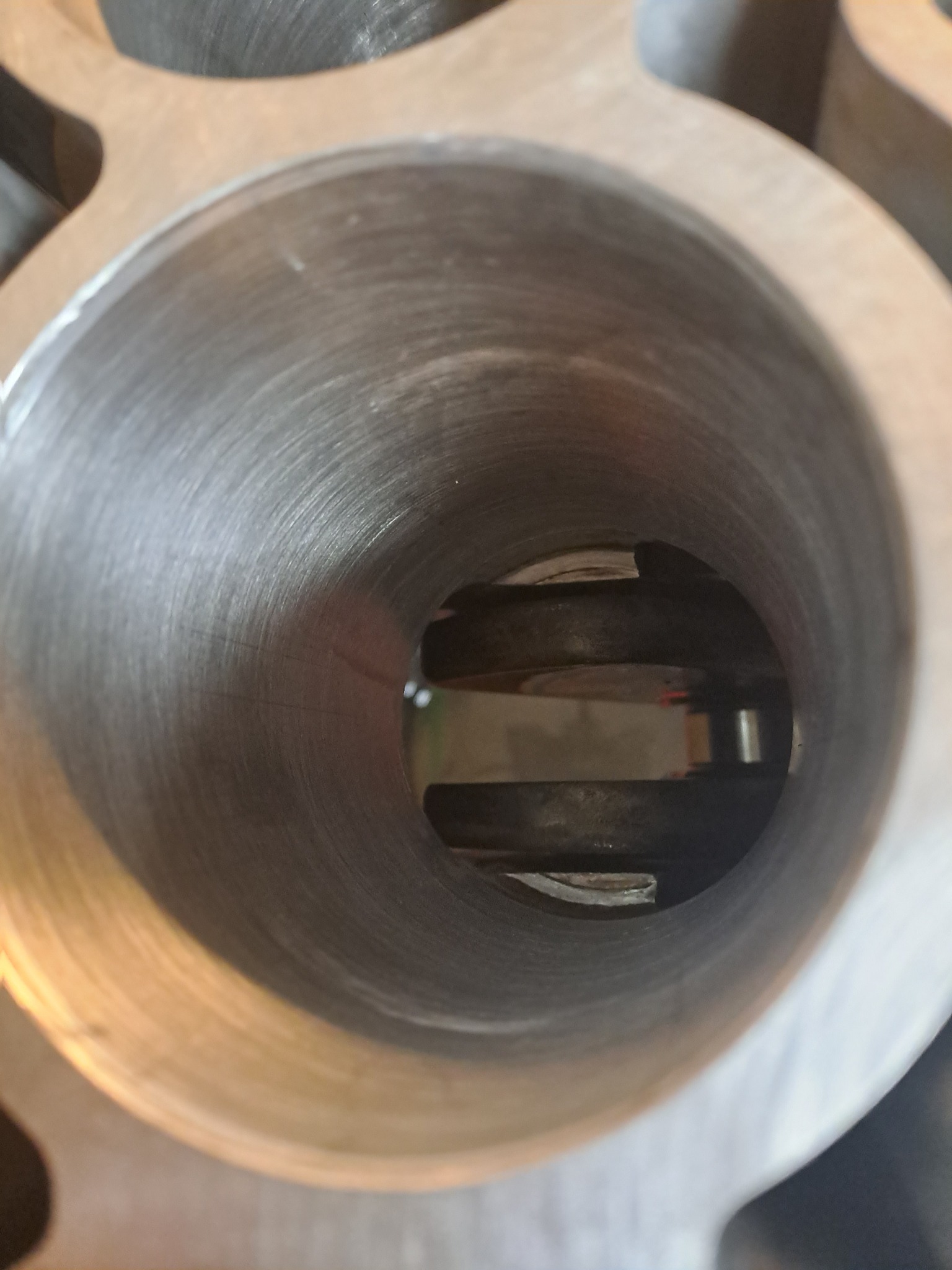 Wnętrze cylindra silnika samochodowego z widocznymi pierścieniami tłokowymi, sfotografowane pod kątem, ukazujące ślady honowania na powierzchni.