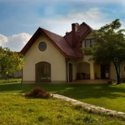 Gotowy dom jednorodzinny z beżową elewacją, czerwoną dachówką, okrągłym oknem i zadbanym trawnikiem z młodym drzewem.