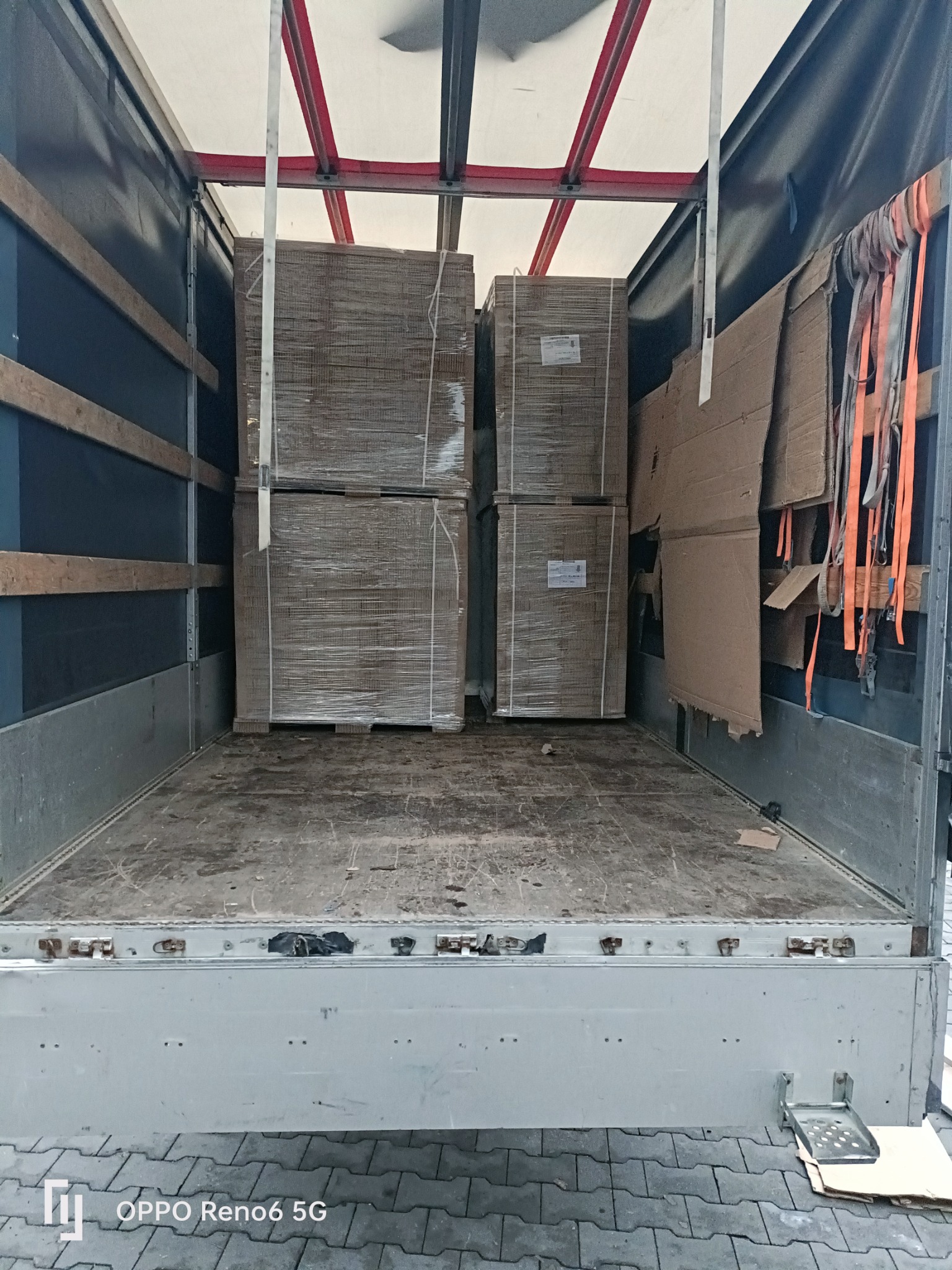 Wnętrze paki busa z załadowanymi paletami owiniętymi folią stretch, zabezpieczonymi kartonami i pasami transportowymi.