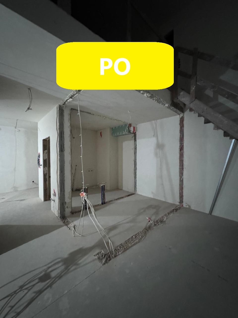 Wnętrze w trakcie prac wyburzeniowych: odsłonięte przewody elektryczne i instalacje, ślady po usuniętych ścianach, fragment schodów w tle.