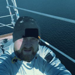 Zakład ogolnobudowlany Rzepka Tomasz Stanisław - Mężczyzna w czapce i bluzie z kapturem robi selfie na rusztowaniu z widokiem na morze i zabudowania na brzegu.