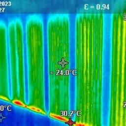 Termowizyjne zdjęcie grzejnika panelowego, ukazujące rozkład temperatur: od 21 stopni Celsjusza u dołu do 30.2 stopni Celsjusza u góry, z zaznaczoną temperaturą około 24 stopni Celsjusza...