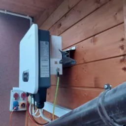 Zamontowany inwerter Sofar na drewnianej ścianie, widoczne kable, przewód uziemiający i gniazda elektryczne.