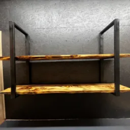 Dwie półki z opalanych desek, osadzone w metalowej, czarnej ramie, zamontowane na ciemnej ścianie z płyty OSB.