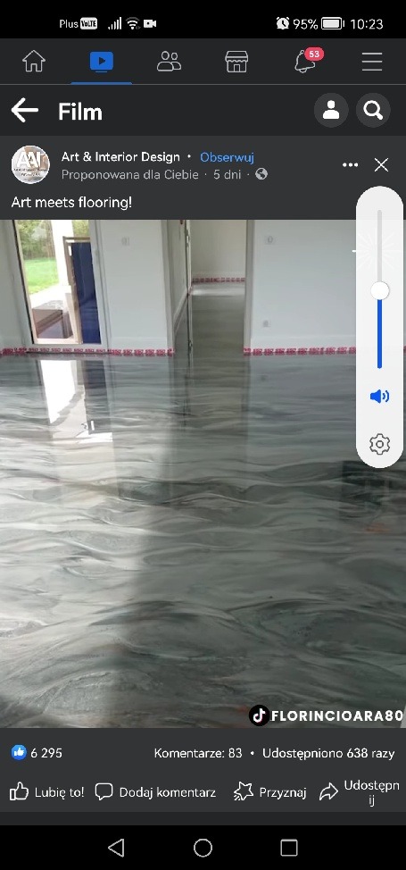 Błyszcząca, szara podłoga żywiczna z marmurkowym wzorem w pustym, jasnym pomieszczeniu z białymi ścianami i widocznymi drzwiami w tle.