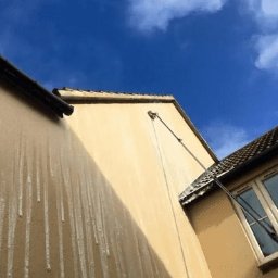 Mdc Michał Góra - Elewacja budynku w trakcie czyszczenia lancą teleskopową, widoczne zacieki wody i fragment okna oraz rynna.