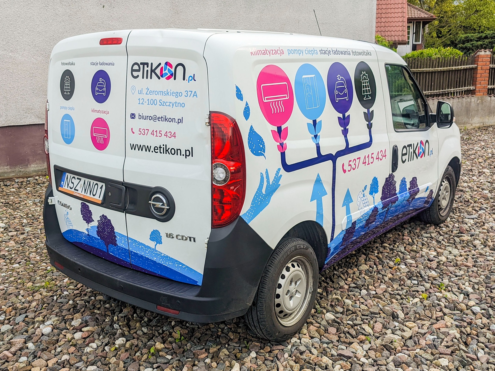 Biały samochód dostawczy z reklamą firmy Etikon.pl, oferującej usługi fotowoltaiki, klimatyzacji, pomp ciepła i stacji ładowania, zaparkowany na żwirowym podłożu.