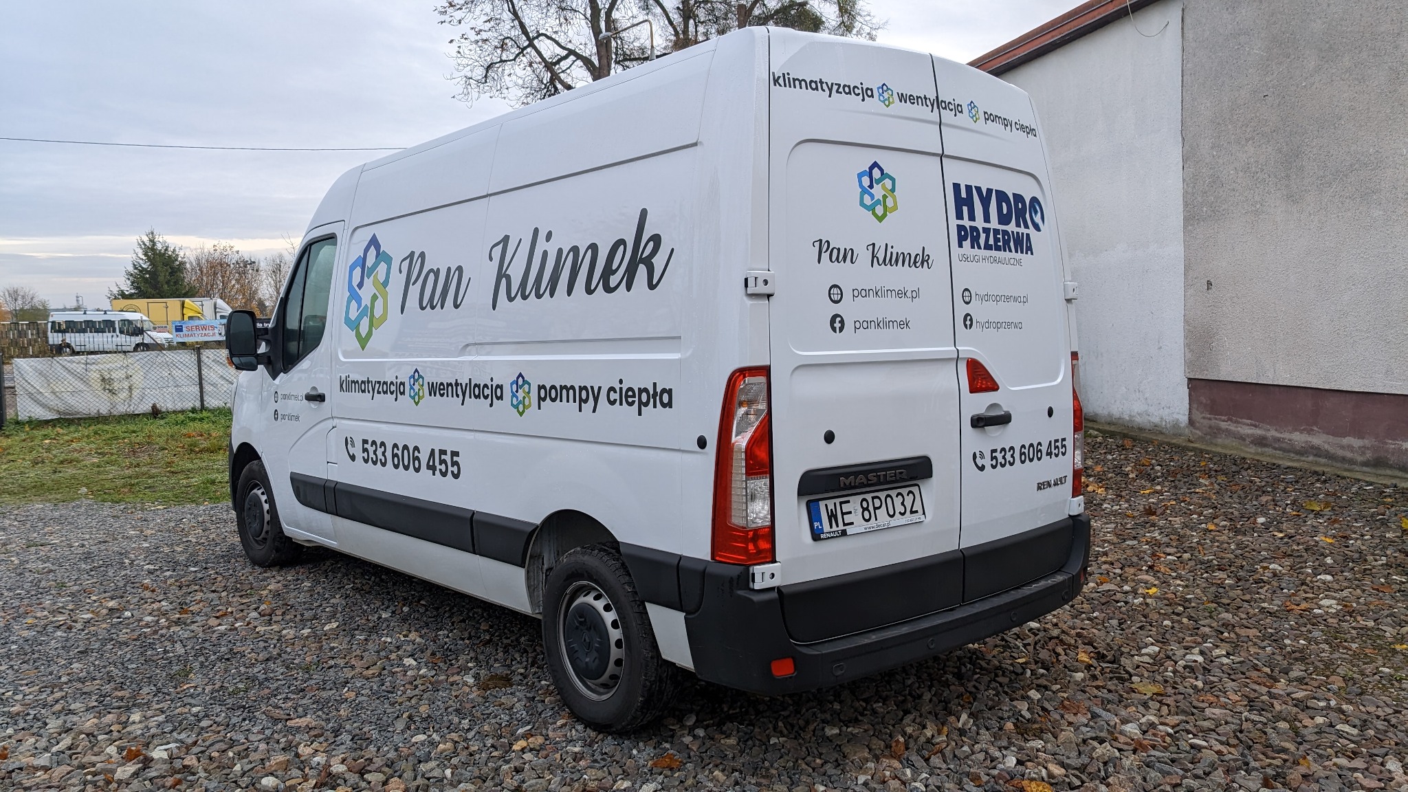 Biały samochód dostawczy z nadrukowanym logo firmy Pan Klimek oferującej usługi klimatyzacji, wentylacji i pomp ciepła, zaparkowany na żwirowym podłożu przed budynkiem.