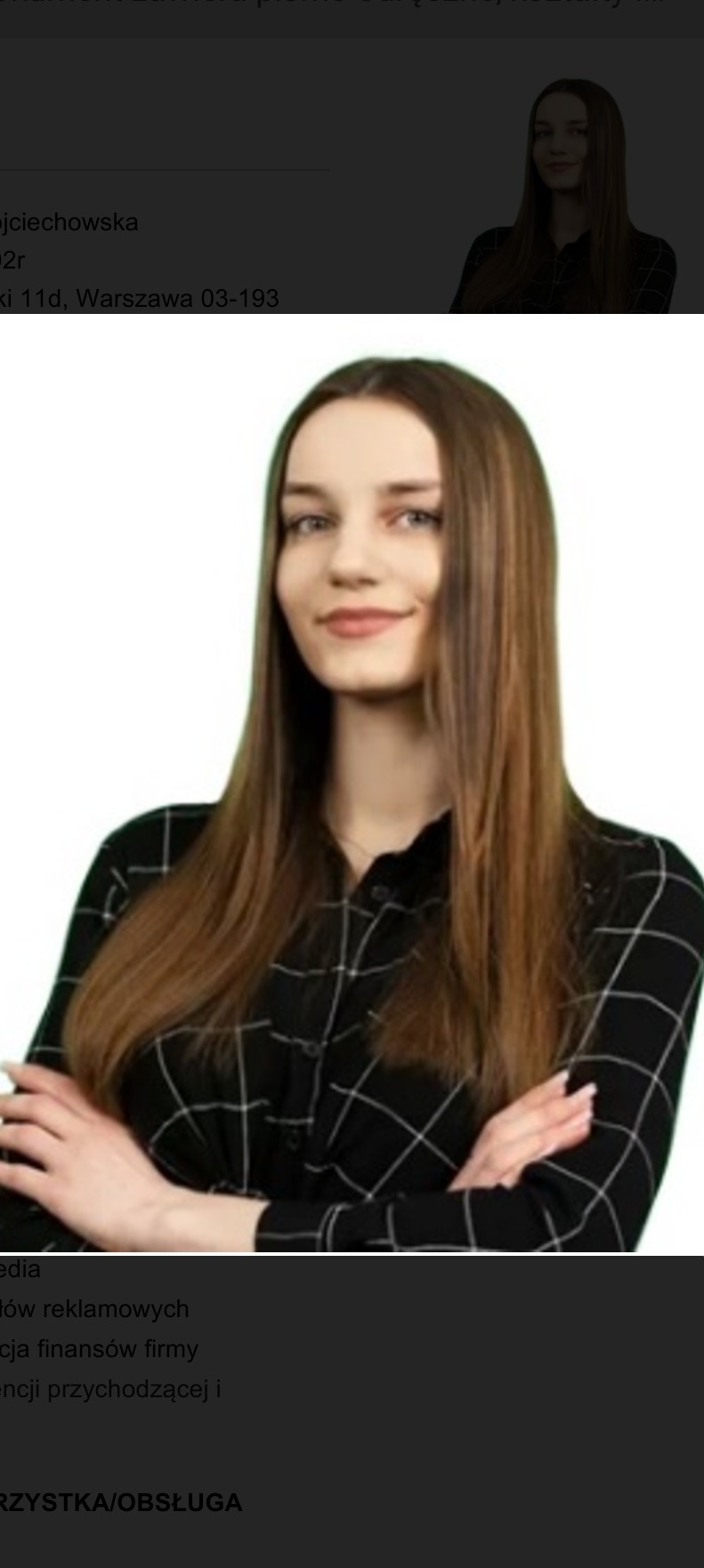 Portret kobiety z długimi, brązowymi włosami, ubranej w czarno-białą koszulę w kratę, z założonymi rękami na tle białej ściany, sugerujący profesjonalizm i pewność siebie.