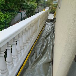 Budrem - Przygotowanie balkonu z białą balustradą do prac remontowych, zabezpieczony folią i taśmą malarską, widok z góry