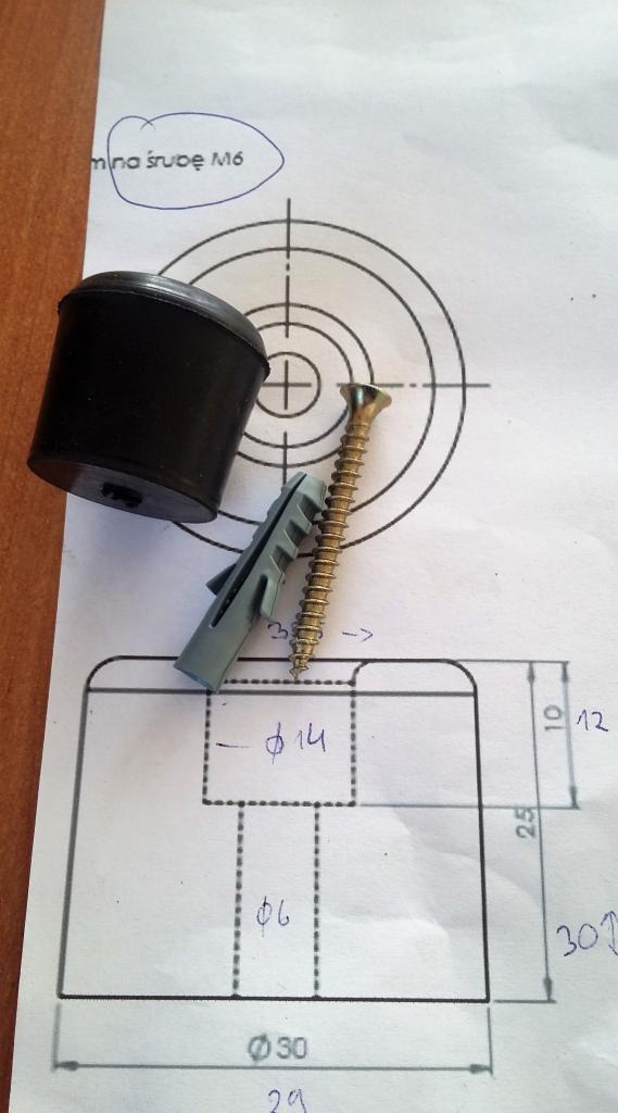 Czarny gumowy odbojnik, kołek rozporowy i śruba na rysunku technicznym z naniesionymi odręcznie wymiarami.