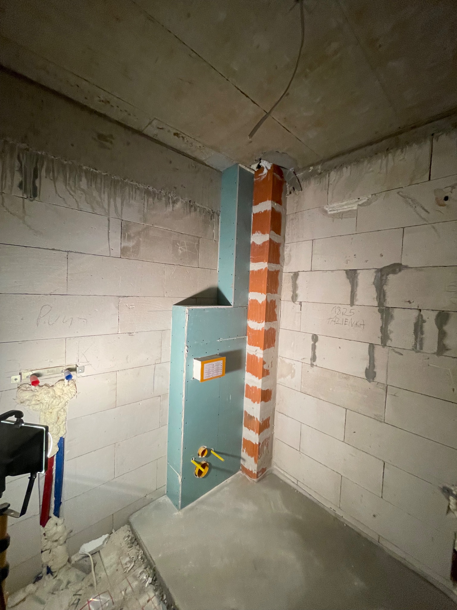 Surowy stan łazienki w Starogardzie Gdańskim, widoczne ściany z betonu komórkowego, piony instalacyjne obudowane płytami gipsowo-kartonowymi i fragment ogrzewania podłogowego.