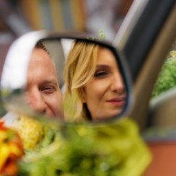 Od Serca Kamil Morawiec - Para młoda widoczna w lusterku samochodu ozdobionego żółtymi kwiatami, ujęcie z bliska.