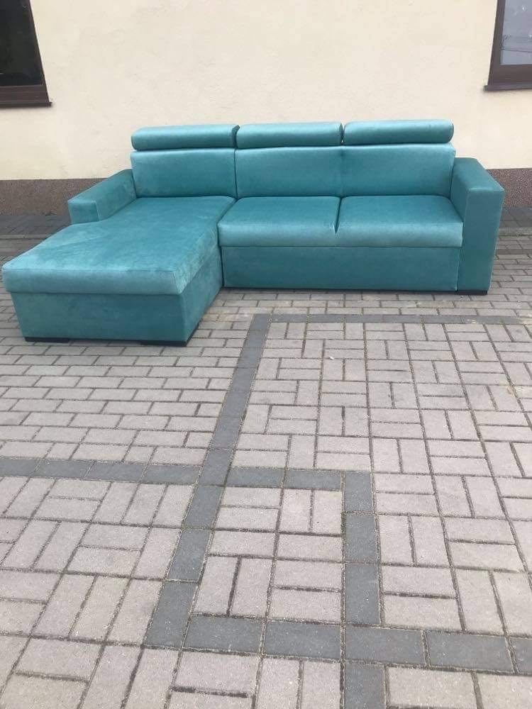 Turkusowy narożnik z zagłówkami na kostce brukowej z szarymi wstawkami, sfotografowany na zewnątrz budynku.