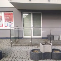 Elewacja budynku z oknem, na którym widnieje reklama agencji reklamowej oferującej projekty graficzne, strony www i sklepy online oraz pozycjonowanie w Google AdWords.