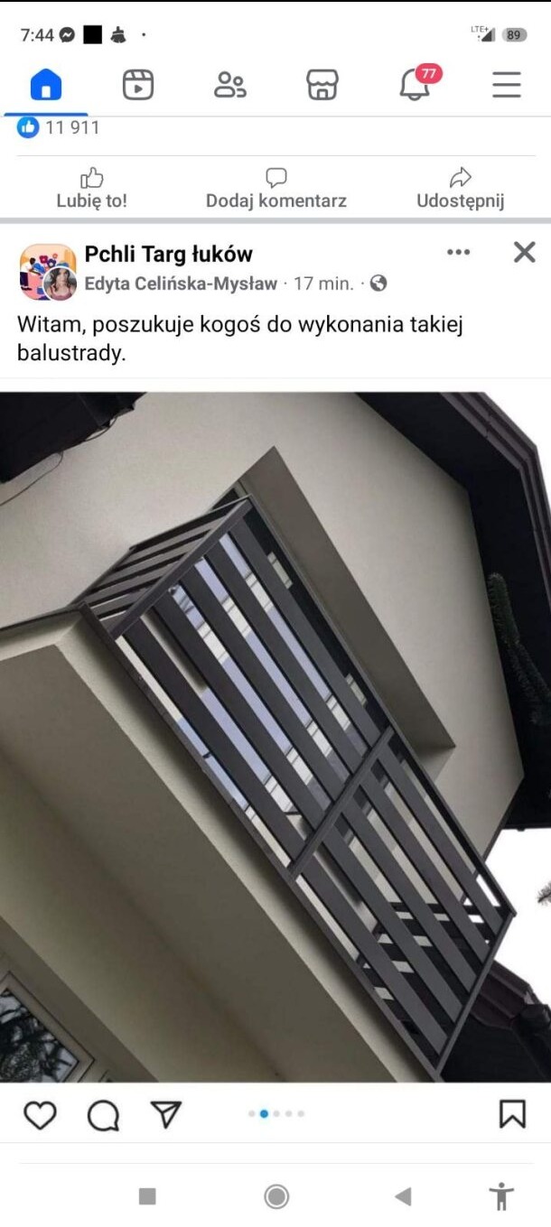 Nowoczesna balustrada balkonowa z ciemnymi, pionowymi profilami, zamontowana na jasnym budynku, widok z dołu pod kątem.