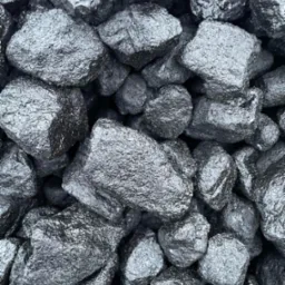 Błyszczące bryły antracytu o nieregularnych kształtach, ułożone blisko siebie, z widoczną fakturą powierzchni i refleksami światła.