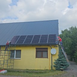 OFF GRID SPÓŁKA Z OGRANICZONĄ ODPOWIEDZIALNOŚCIĄ - Dwóch monterów instaluje panele słoneczne na dachu żółtego domu jednorodzinnego; jeden na rusztowaniu, drugi na drabinie, widoczny samochód dostawczy z boku.