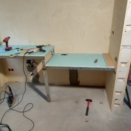 Valeria BUD Vasyl Trachuk - Wnętrze w trakcie prac wykończeniowych: szkielet konstrukcji z profili metalowych pod zabudowę z płyt, narzędzia (wiertarka, szlifierka kątowa, poziomica) na górze, młotek na podłodze, fragment...