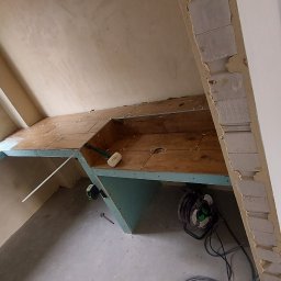 Valeria BUD Vasyl Trachuk - Konstrukcja z płyty karton gips na stelażu, przygotowana pod zabudowę wnęki okiennej i blatu, z widocznymi narzędziami i materiałami budowlanymi w tle.