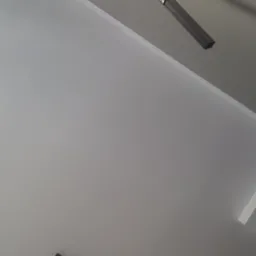 Czarny, regulowany reflektor sufitowy na szynie, zamontowany na białym suficie, widziany pod kątem.