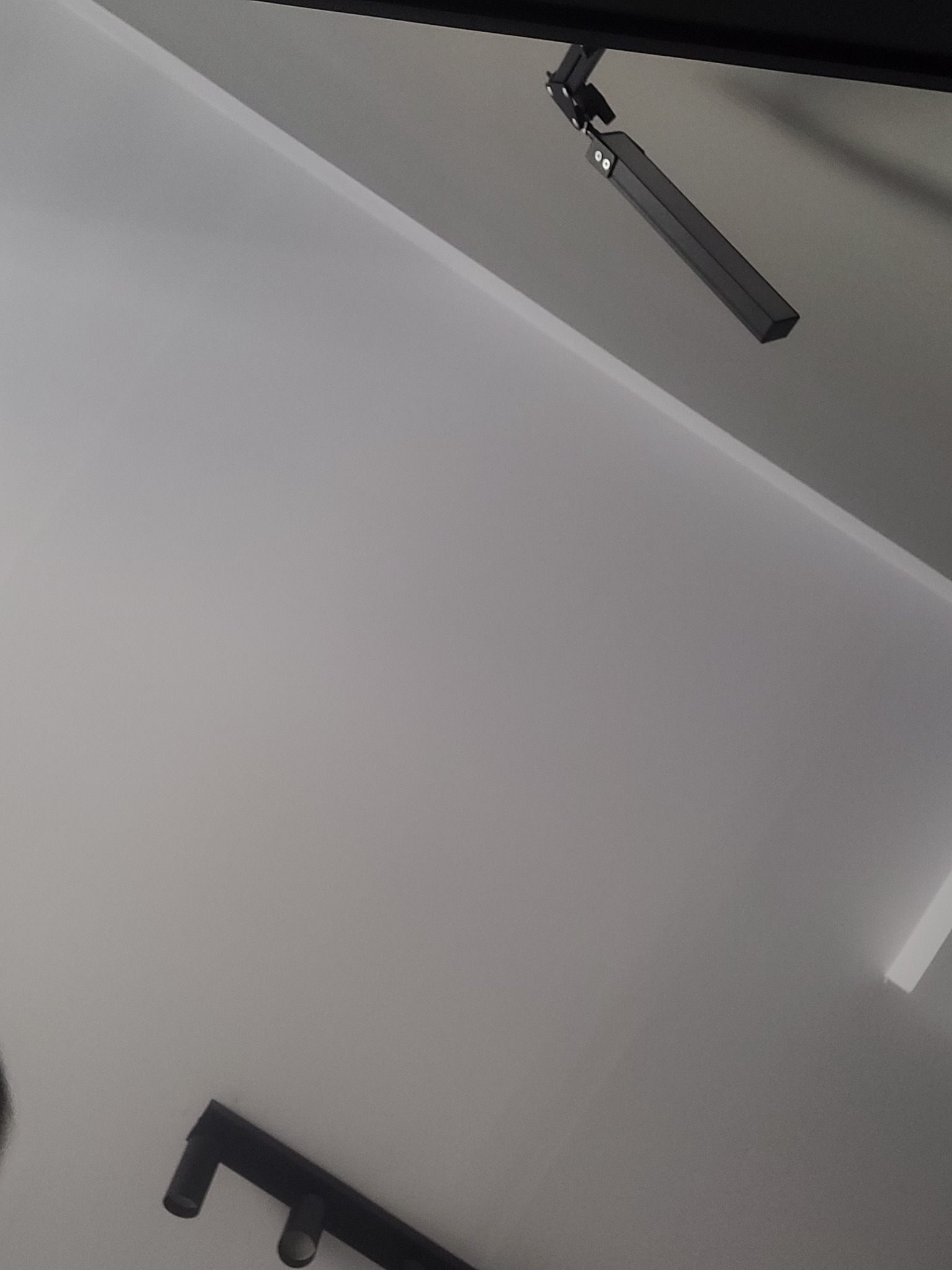 Czarny, regulowany reflektor punktowy zamontowany na białym suficie, widoczny pod kątem.