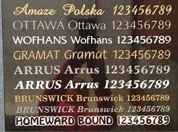 Tablica z wygrawerowanymi nazwami firm i numerami telefonów w różnych stylach czcionek, prawdopodobnie wzornik do wyboru przez klienta.