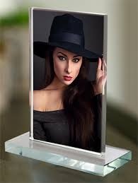 Szklana ramka na zdjęcie portretowe kobiety w czarnym kapeluszu, ustawiona na przezroczystej, prostokątnej podstawie.