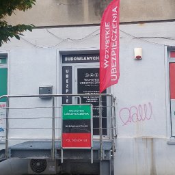 WSZYSTKIE UBEZPIECZENIA ANNA RESZKE - Fasada biura ubezpieczeń z reklamami 'Tanie OC', 'Dobre AC', 'Wszystkie ubezpieczenia', flaga reklamowa i schody wejściowe. Widoczne numery telefonów i nazwa firmy.