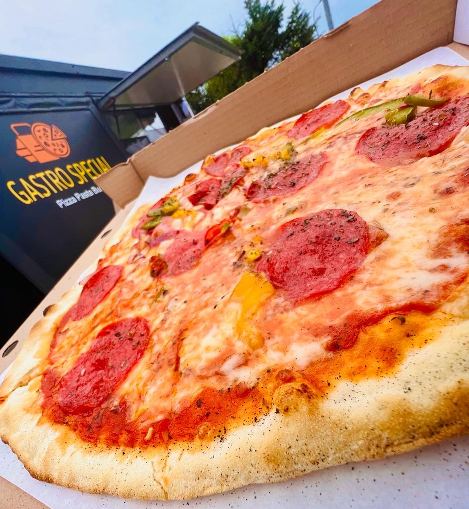 Pizza pepperoni z papryką w kartonowym pudełku, widoczny food truck Gastro Special w tle.