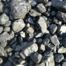 Kupa błyszczących brył antracytu o nieregularnych kształtach, oświetlonych z góry, z widocznymi refleksami świetlnymi na powierzchniach.