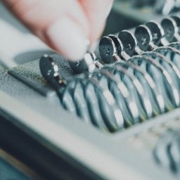 Jan Janota - Dłoń z delikatnym manicure wybiera srebrny pierścionek z numerem rozmiaru z ekspozytora jubilerskiego.