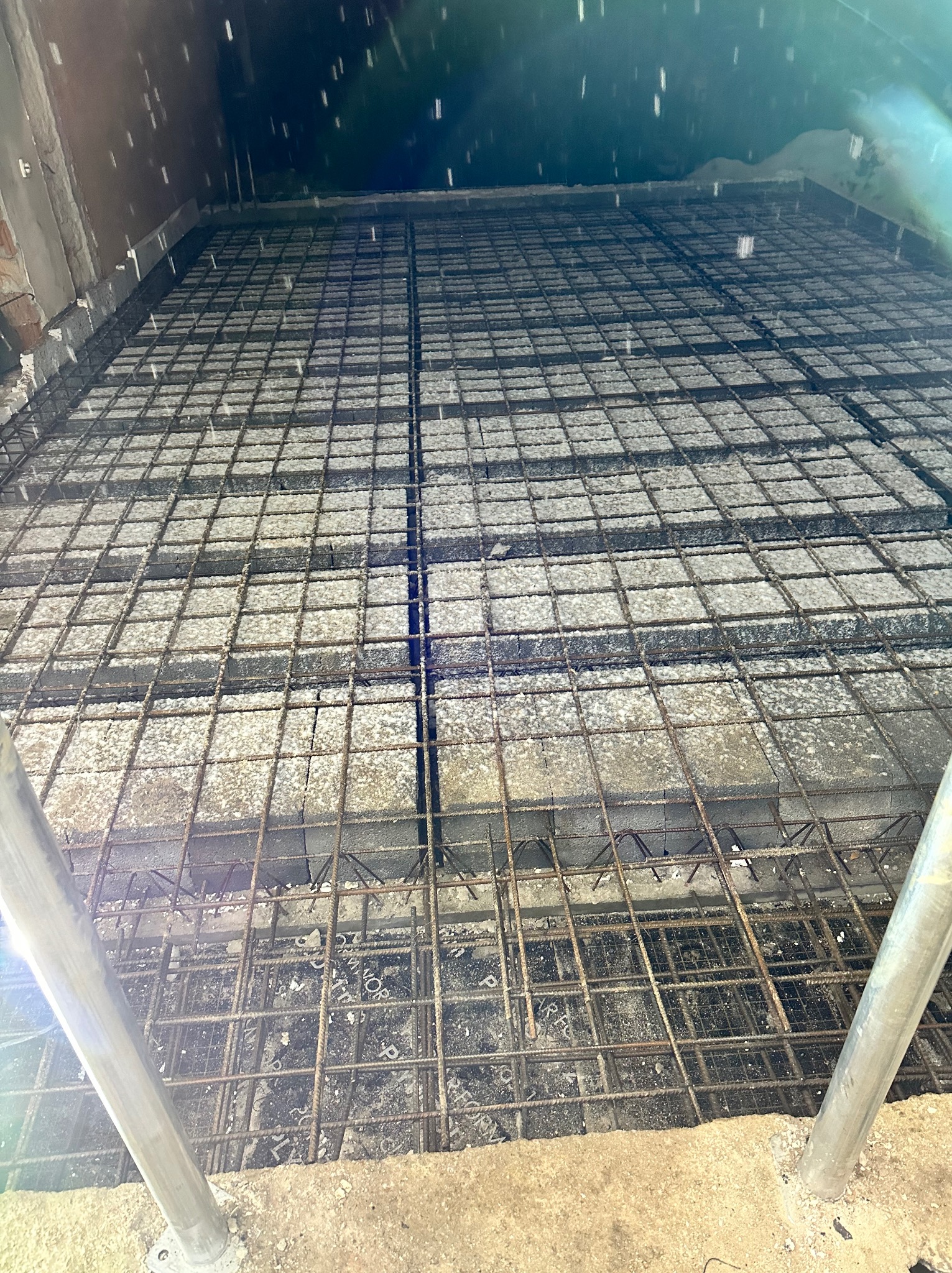 Zbrojenie pod wylewkę betonową na podłożu z izolacją, widok z dołu, z rurami wspornikowymi.