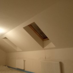 M-BUD Sp. z o.o. - Poddasze po remoncie, świeżo pomalowane na jasny kolor, z oknem dachowym i grzejnikami. Folia ochronna na podłodze zabezpiecza przed zabrudzeniem.