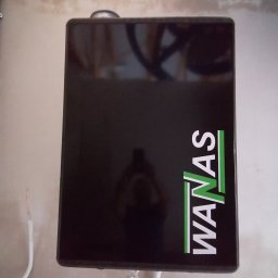 Eko-Mont- Klimatyzacja Wentylacja - Czarna skrzynka rekuperatora z logo WANAS zamontowana na ścianie, widoczne przewody elektryczne i rurki instalacyjne.