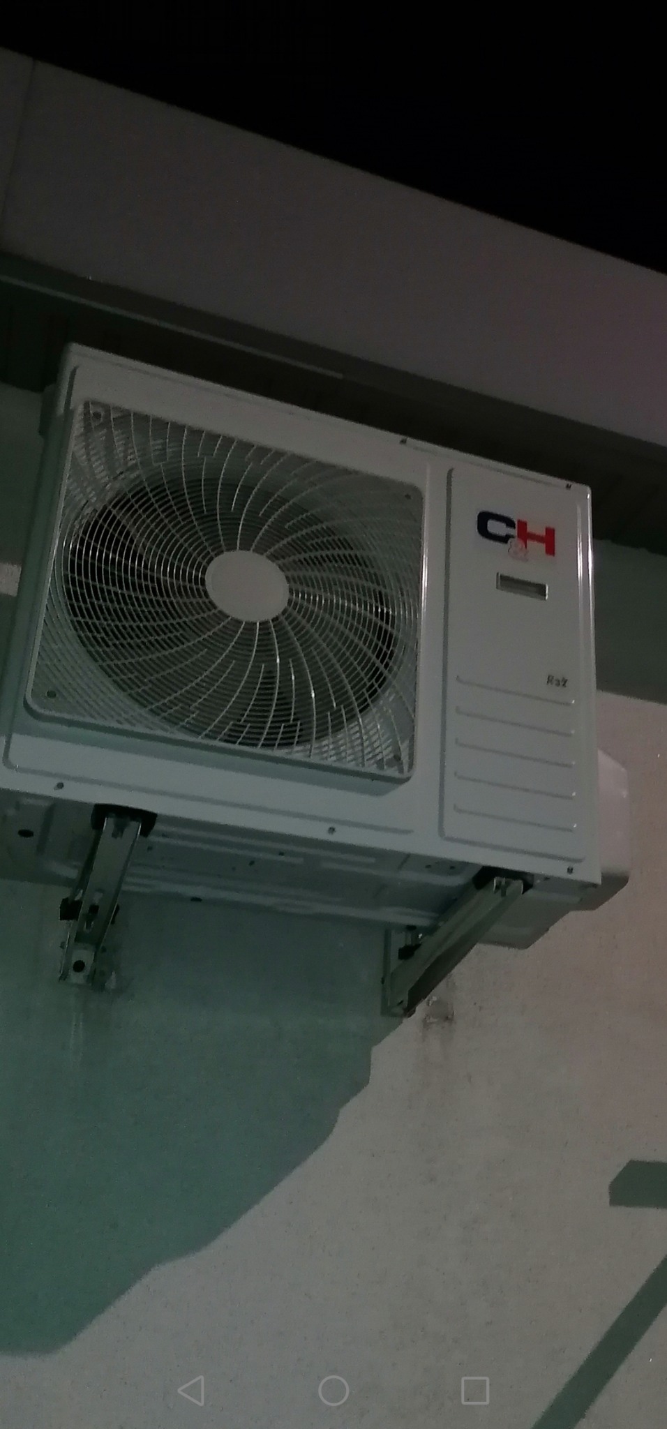 Zewnętrzna jednostka klimatyzacji marki CH zamontowana na szarej ścianie budynku, widoczne metalowe wsporniki montażowe.