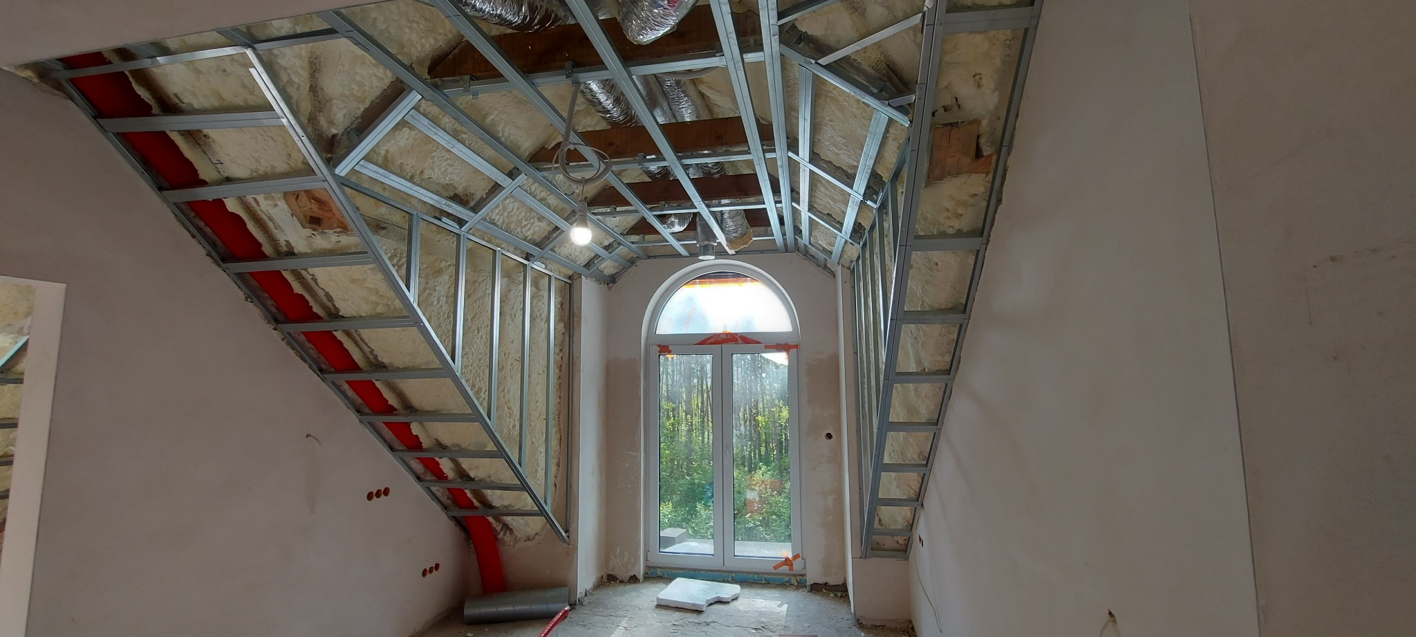 Montaż stelaża pod zabudowę poddasza z oknem w Poznaniu, widoczna izolacja i kanały wentylacyjne, ściany przygotowane do dalszych prac.