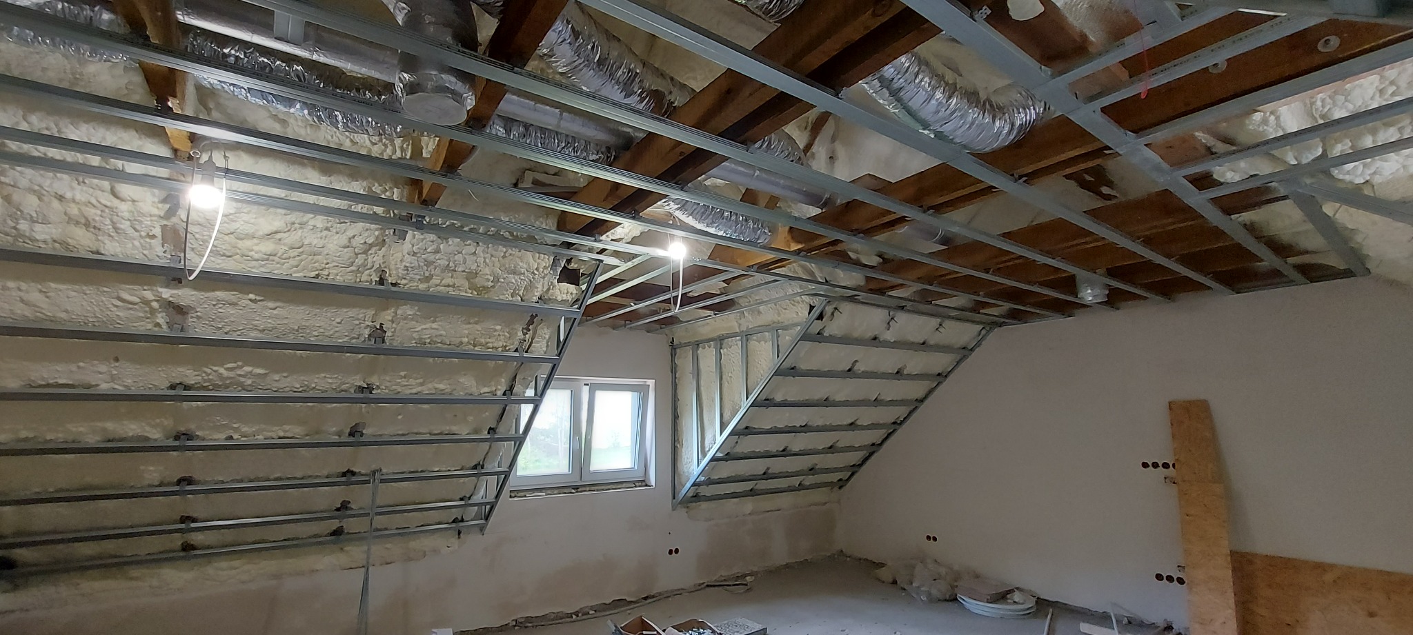 Montaż metalowej konstrukcji pod zabudowę poddasza z widoczną izolacją piankową na skosach i elementami wentylacji pod dachem