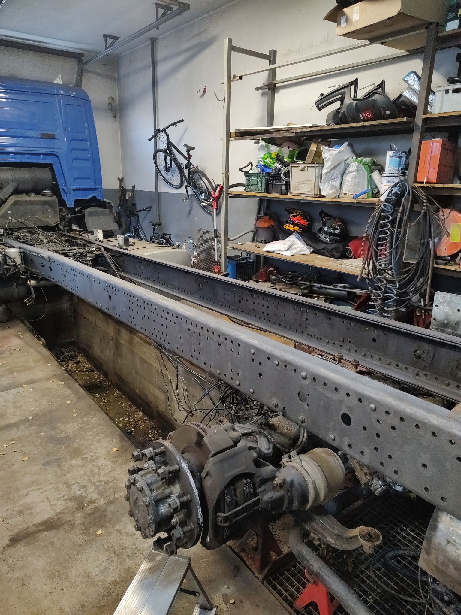 Podwozie ciężarówki z widocznymi elementami zawieszenia, w warsztacie, rama po oczyszczeniu, przygotowana do dalszych prac.