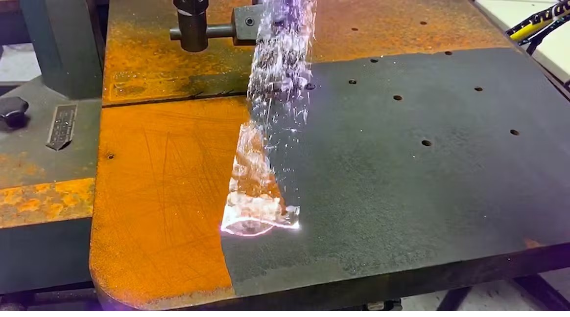 Strumień wody pod ciśnieniem usuwa rdzę z metalowej powierzchni, odsłaniając czysty metal.