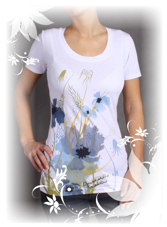 Kobieta prezentuje białą koszulkę z krótkim rękawem i niebiesko-żółtym kwiatowym nadrukiem, z widocznym napisem 'Dynamite Fashion'.