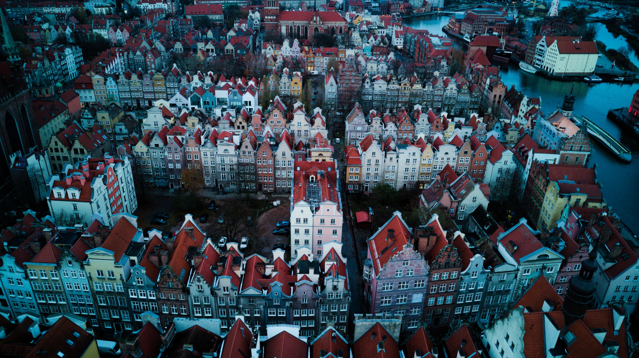 Panorama lotnicza Gdańska z charakterystycznymi czerwonymi dachami kamienic, widok z drona na Stare Miasto w pochmurny dzień.