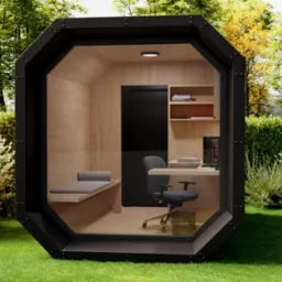 Nowoczesna, przeszklona kabina biurowa w kształcie ośmiokąta, umieszczona na trawniku w ogrodzie, z widocznym wnętrzem: biurko, krzesło, półki z książkami i mała leżanka.