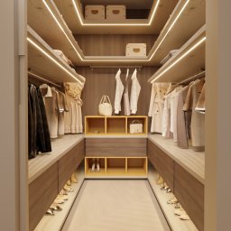Kaolin Interiors Karolina Grzywa - Przestronna garderoba z oświetleniem LED, beżowymi meblami z drewna i półkami na buty, z wiszącymi ubraniami i torebkami.