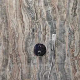 Bateria prysznicowa z deszczownicą na ścianie z dekoracyjnym wzorem imitującym marmur w odcieniach szarości, brązu i beżu, nad białą wanną.