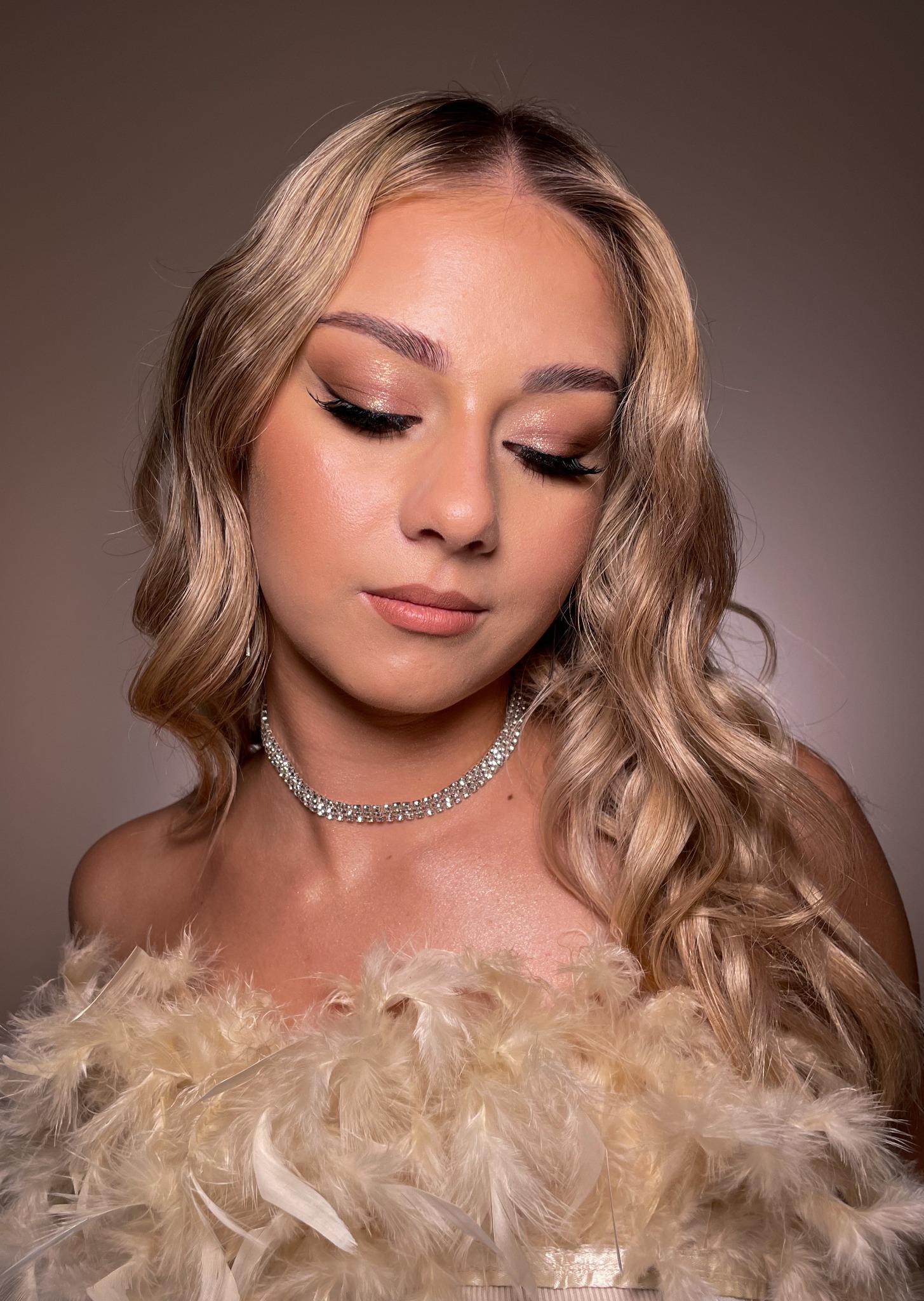 Portret kobiety z zamkniętymi oczami, prezentującej wieczorowy wygląd z błyszczącym cieniem do powiek, czarnym eyelinerem, sztucznymi rzęsami, podkreślonymi kośćmi policzkowymi, subtelną szminką...