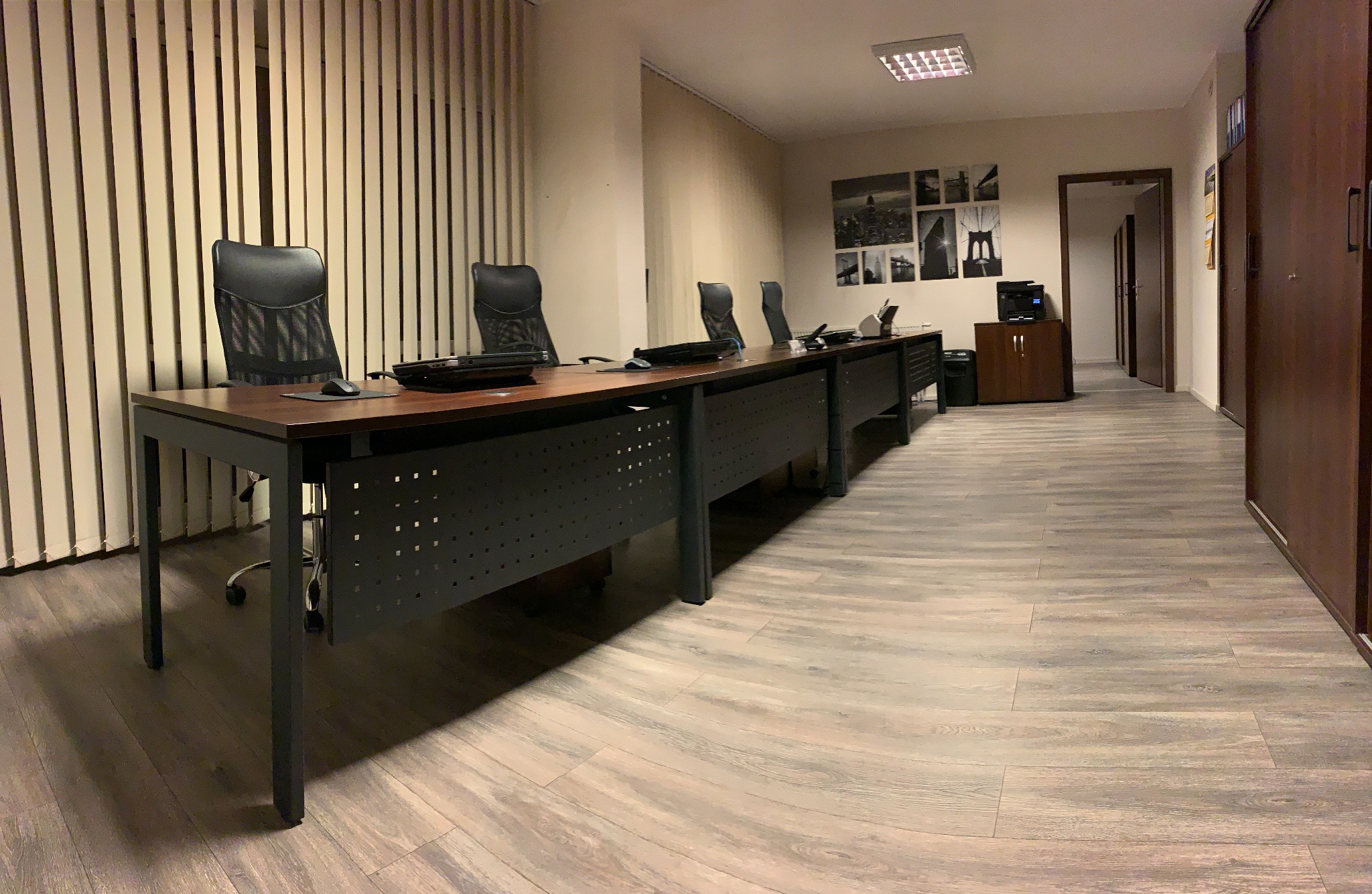 Nowoczesne biuro z długim stołem konferencyjnym, krzesłami biurowymi i minimalistycznym wystrojem.