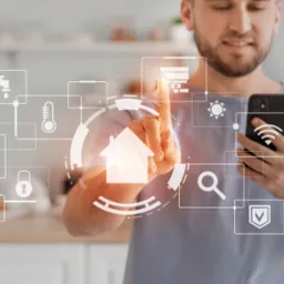 Mężczyzna dotyka palcem interfejsu inteligentnego domu wyświetlanego nałożonego na obraz z telefonu, widoczne ikony: kran, termometr, ekran, zamek, koło zębate, słońce, dom, lupa, wifi, ochrona.