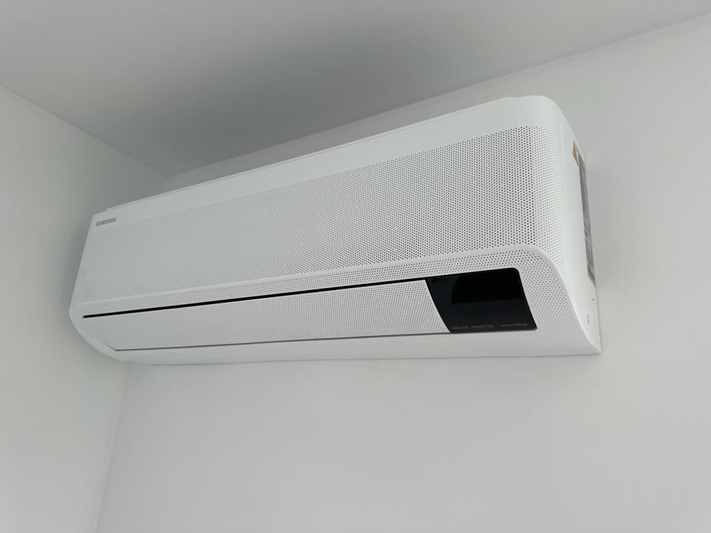 Biała klimatyzacja Samsung Digital Inverter zamontowana na białej ścianie, widok z dołu, minimalistyczny design.